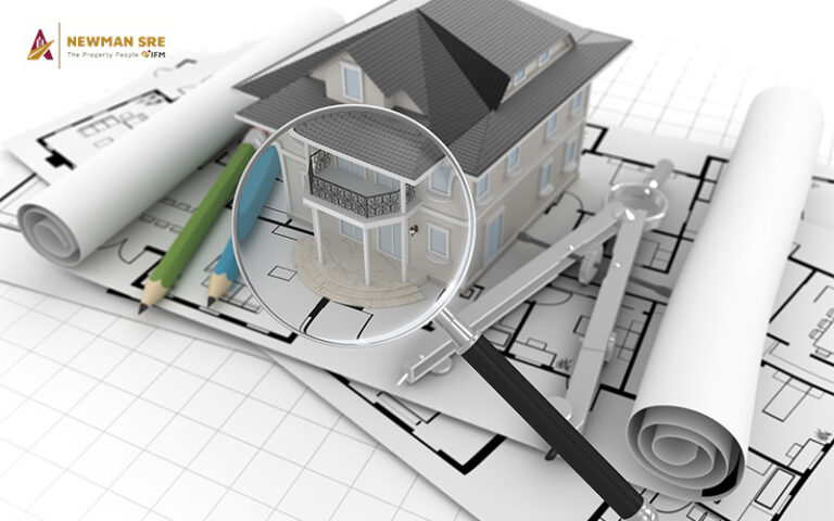 A magnifying glass over a house blueprint.