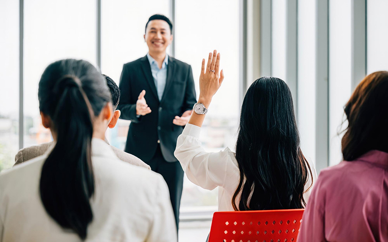 Attendee raising a hand to vote during a meeting.