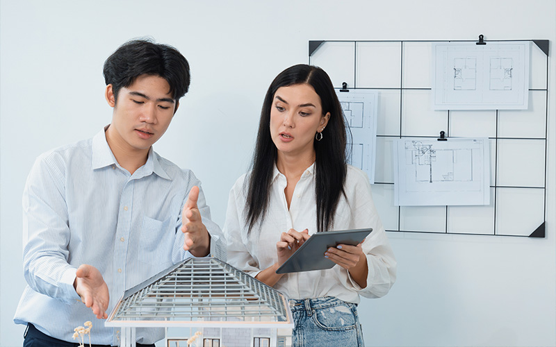 Professionals discussing architectural models using a tablet.