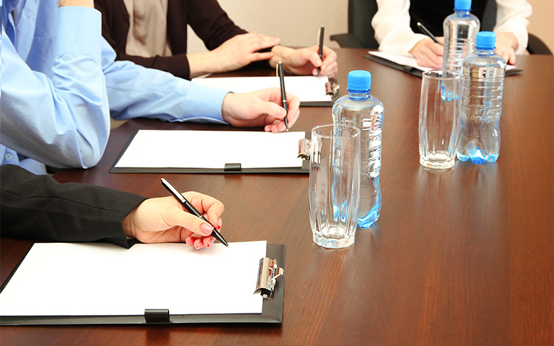 Close-up of council members taking notes during a meeting.