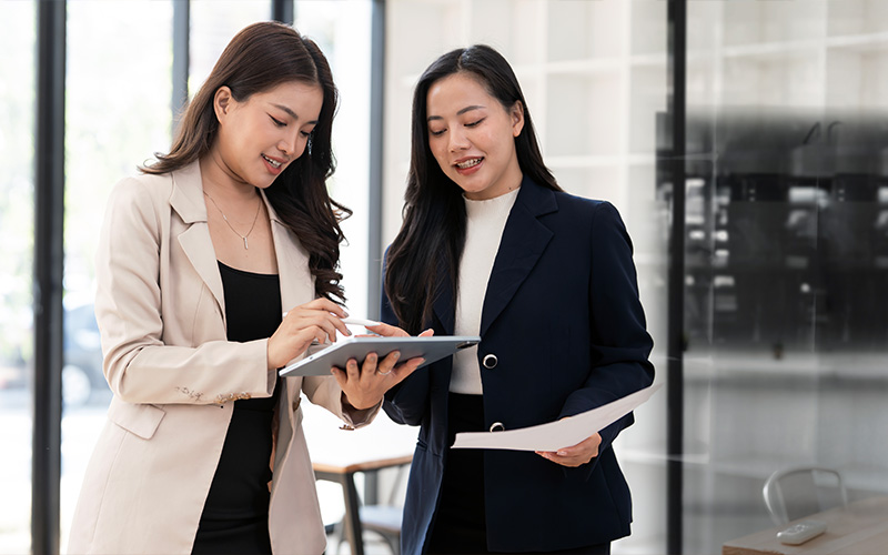 Two business professionals discussing strategic operations on a tablet.
